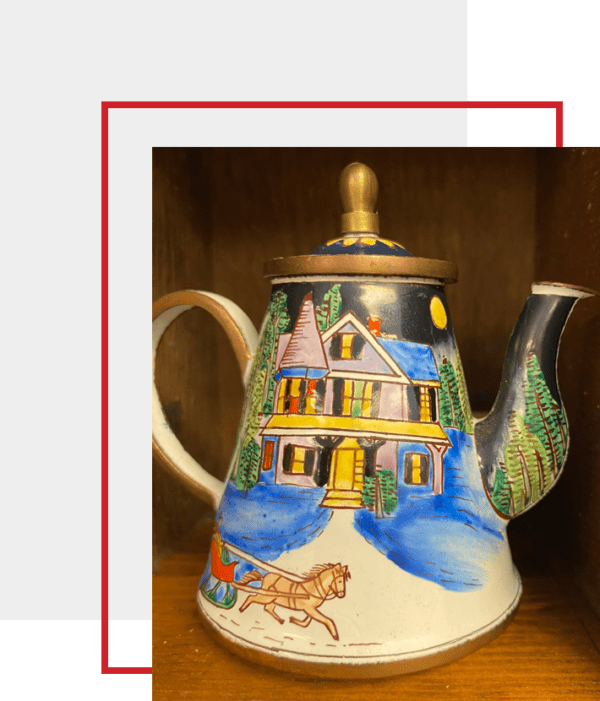 A teapot with a picture of a house on it.