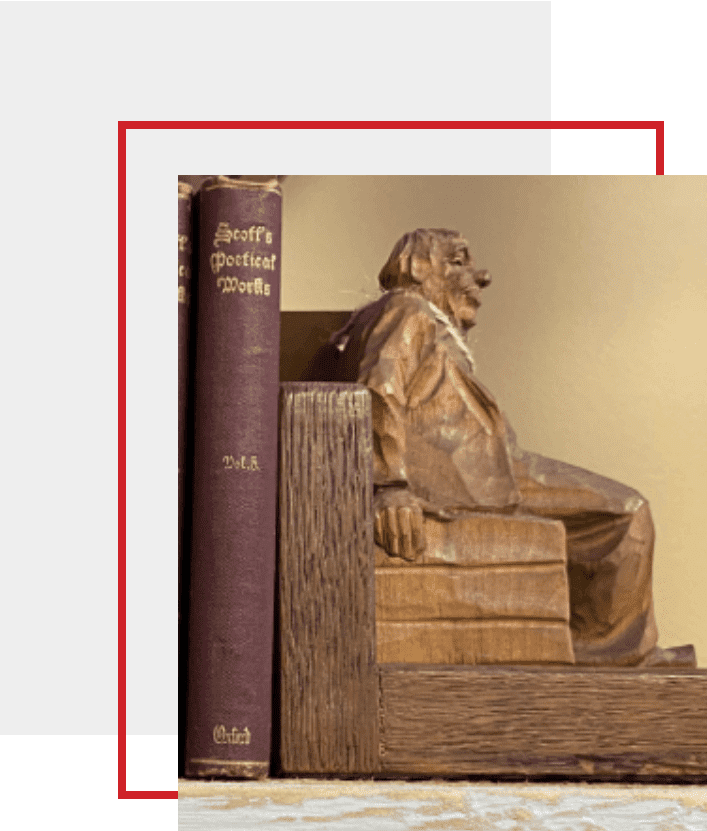 A wooden statue of a man sitting on top of books.