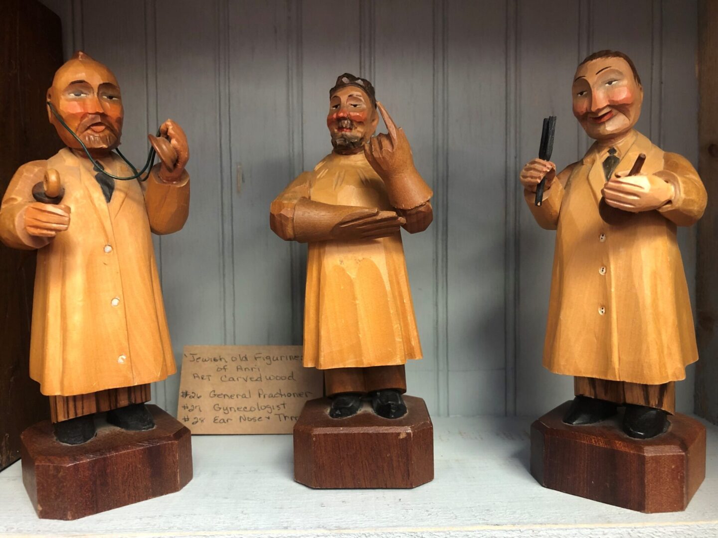 Three statues of men in yellow coats and hats.