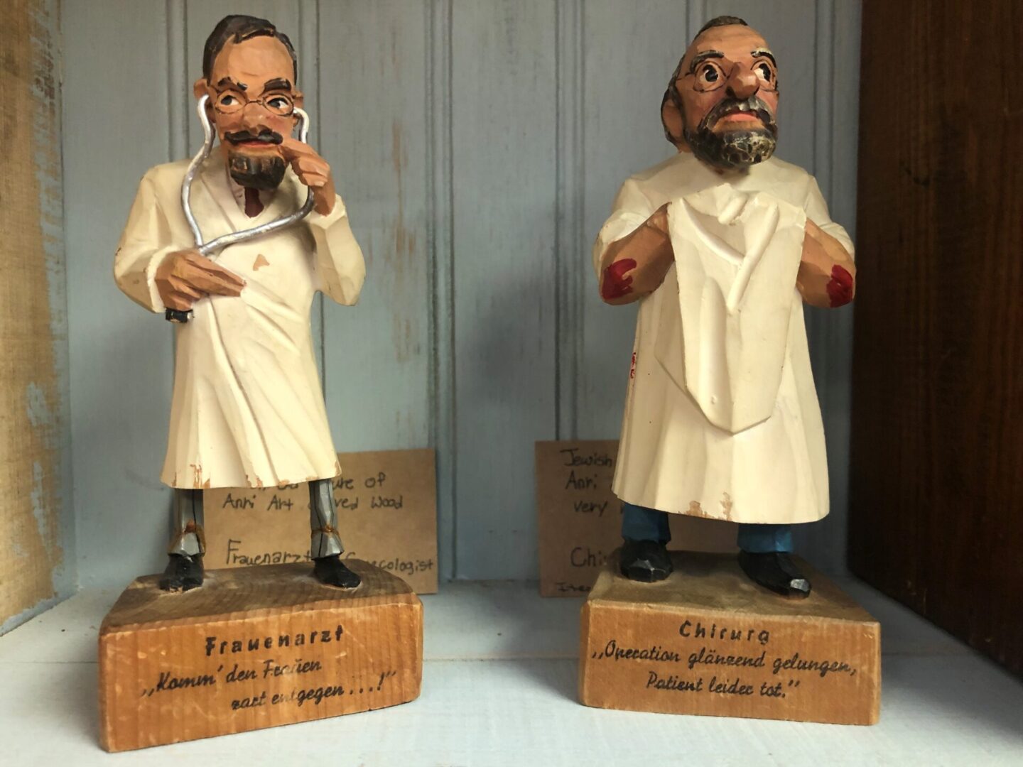 Two figurines of a man in white robes and glasses.
