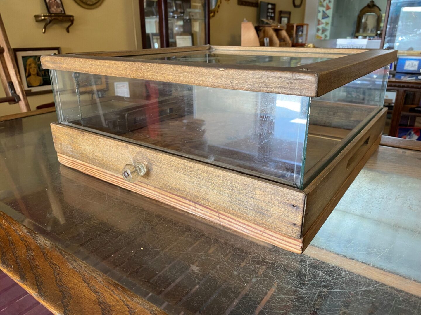 A wooden box with glass display top on a table.
