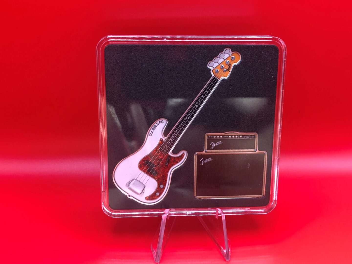 A DYNAMIC DUO - 2X Fine Silver Shaped Coin Set bass guitar and amp on a vibrant red background, forming a dynamic duo.