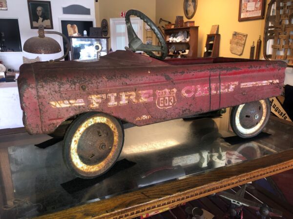 A red fire truck toy car sitting on top of a table.