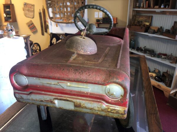 A red and white car is in the middle of a room.